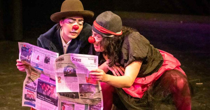 Two clowns look in a newspaper.