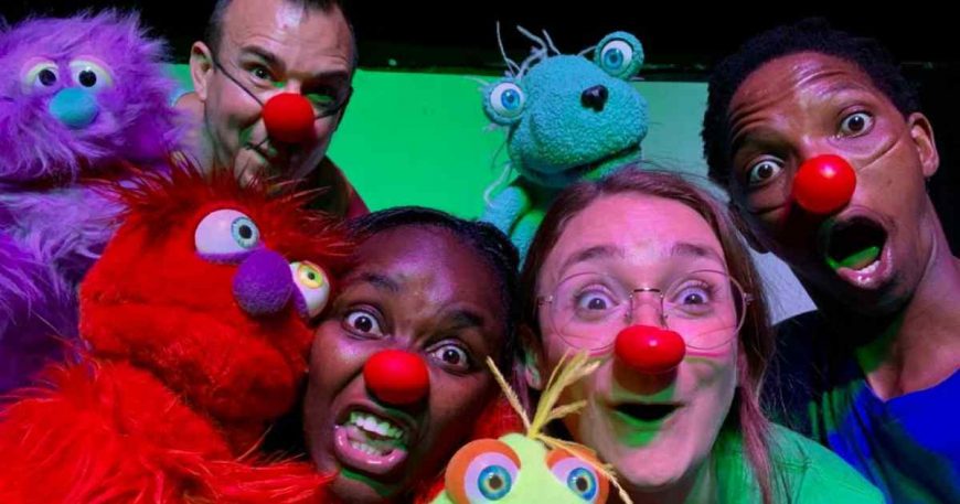 Clowns with colorful puppets crowd together for the camera