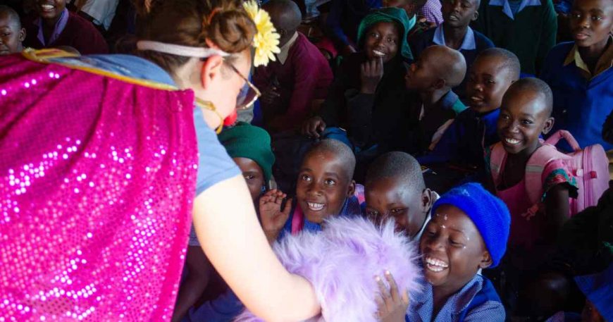 A clown, defending kids' right to play in Zimbabwe, shares a puppet with a young boy.