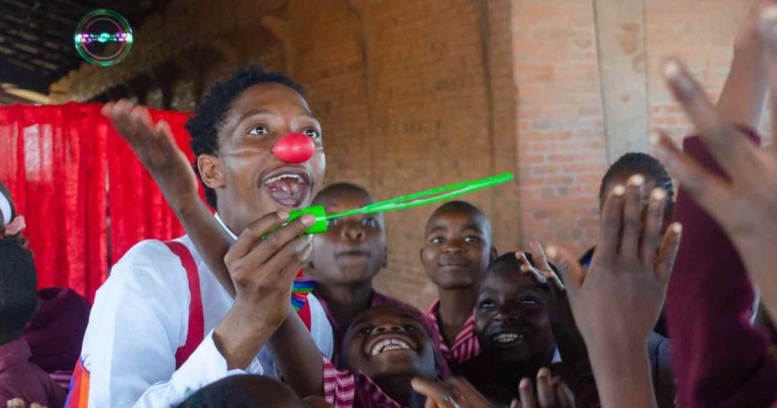 Cadrick blows bubbles with kids after a clown show.