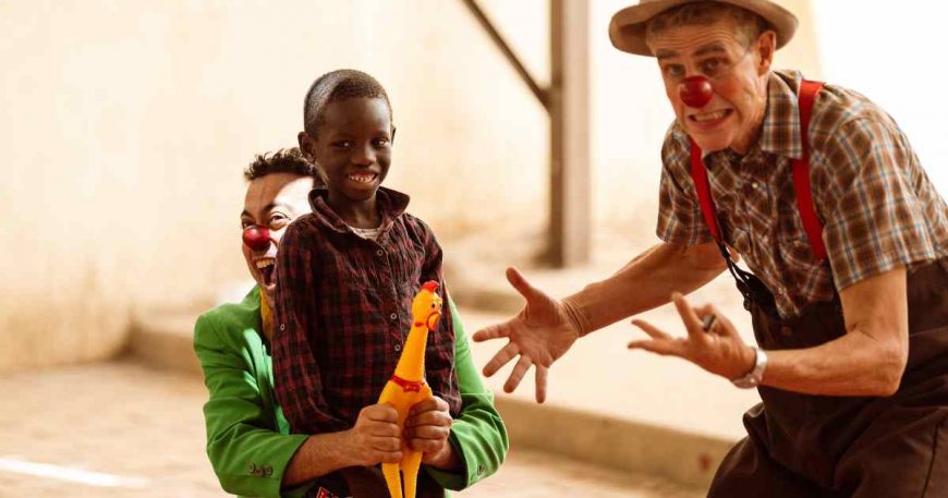 Clowns acting silly with a rubber chicken for a kid's amusement