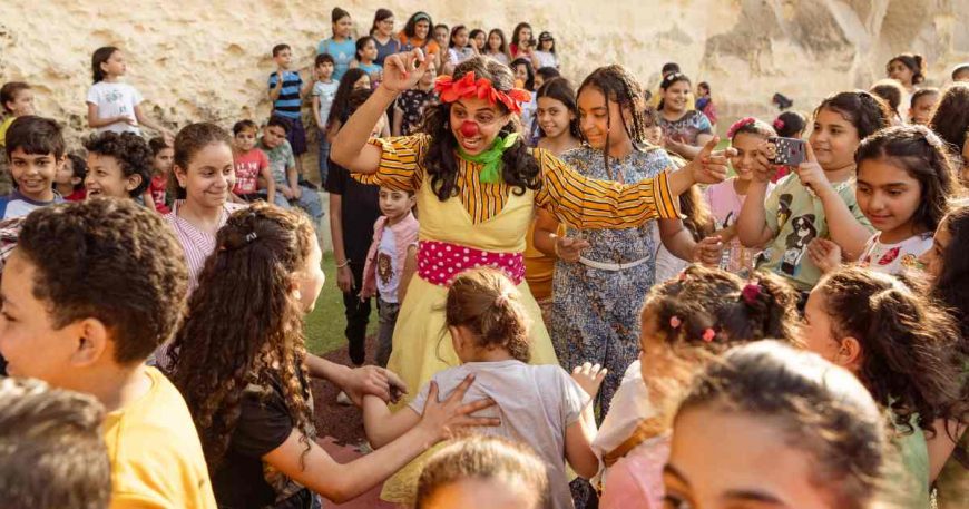 Kids surrounding a woman clown